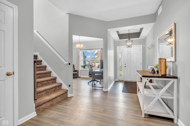 entrance foyer featuring baseboards, stairs, wood finished floors, and a tray ceiling