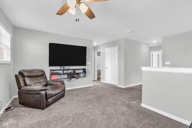 living area with baseboards, a ceiling fan, and carpet