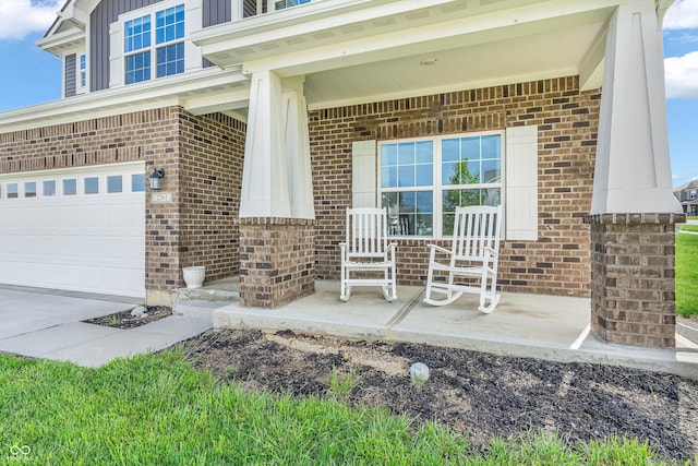 doorway to property with covered porch, brick siding, and an attached garage