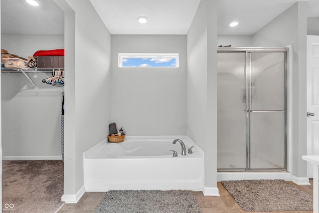 full bathroom featuring a walk in closet, a shower stall, recessed lighting, and a garden tub