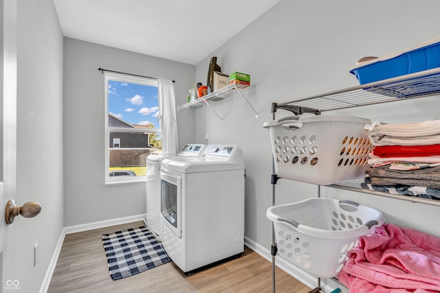 laundry area featuring washing machine and clothes dryer, laundry area, baseboards, and light wood-type flooring