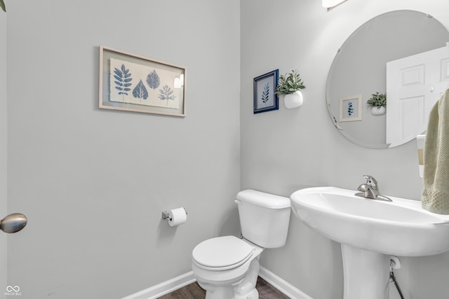 bathroom featuring baseboards, a sink, wood finished floors, and toilet
