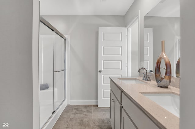 bathroom with a sink, baseboards, a shower stall, and double vanity
