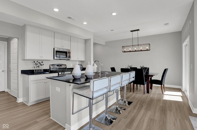kitchen featuring visible vents, dark countertops, light wood-style floors, white cabinetry, and appliances with stainless steel finishes