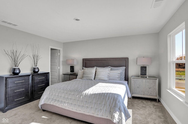 bedroom with baseboards, visible vents, and light carpet