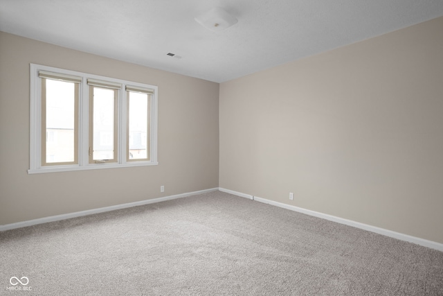 empty room with carpet floors, baseboards, and visible vents