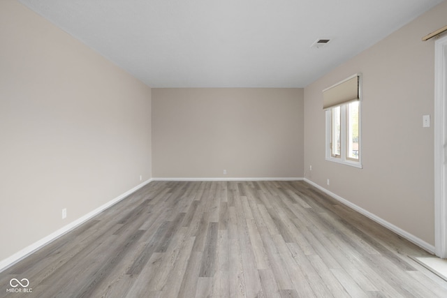 empty room with light wood-type flooring, baseboards, and visible vents