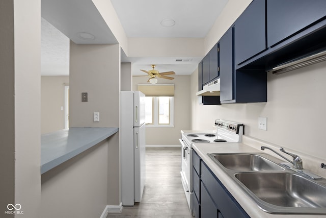 kitchen with a sink, blue cabinets, under cabinet range hood, and white appliances