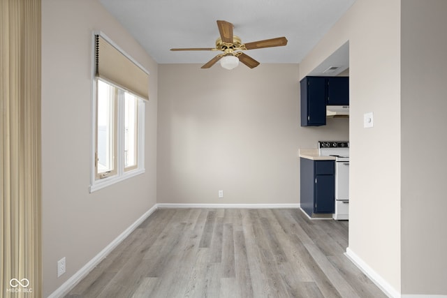 interior space with electric stove, ceiling fan, under cabinet range hood, and blue cabinetry