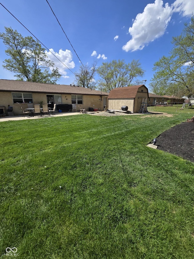 rear view of property featuring brick siding, an outdoor structure, a shed, a yard, and a patio