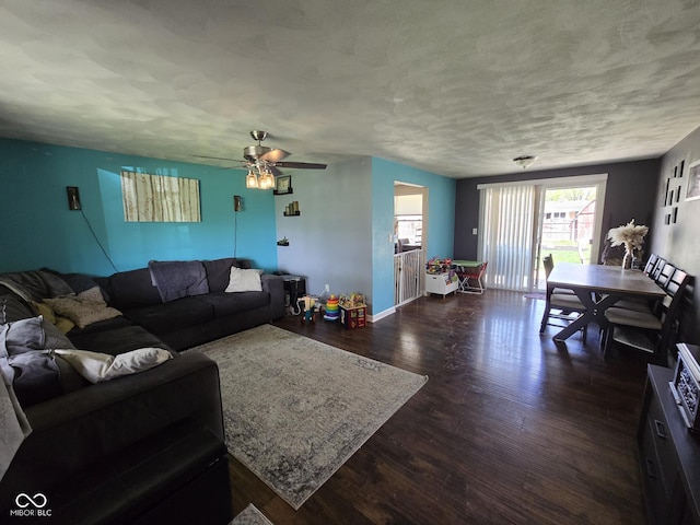 living room featuring a textured ceiling, ceiling fan, dark wood finished floors, and baseboards