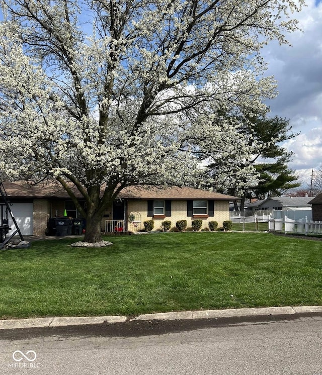 single story home featuring brick siding, fence, and a front yard