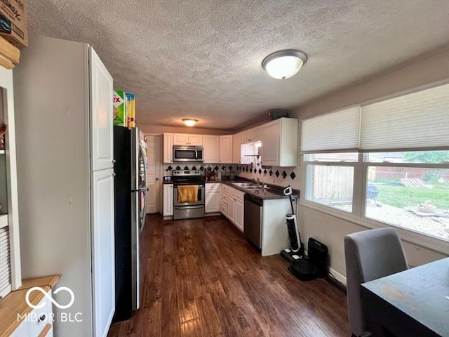 5218 Fletcher St, Anderson, IN 46013 - kitchen featuring appliances with stainless steel finishes, a sink, a textured ceiling, dark countertops, and dark wood finished floors