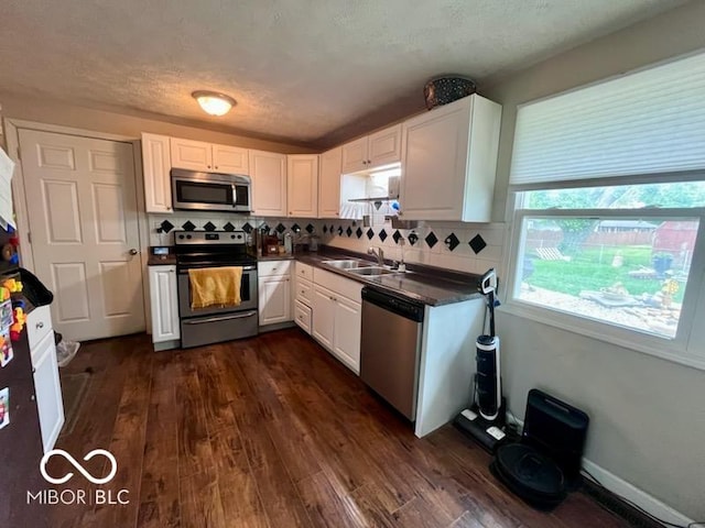 5218 Fletcher St, Anderson, IN 46013 - kitchen featuring appliances with stainless steel finishes, a sink, dark countertops, white cabinets, and tasteful backsplash