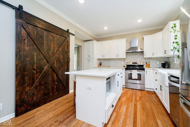 11141 Saybrook Ct, Fishers, IN 46037 - kitchen with stainless steel appliances, wall chimney exhaust hood, a barn door, light countertops, and light wood-style floors