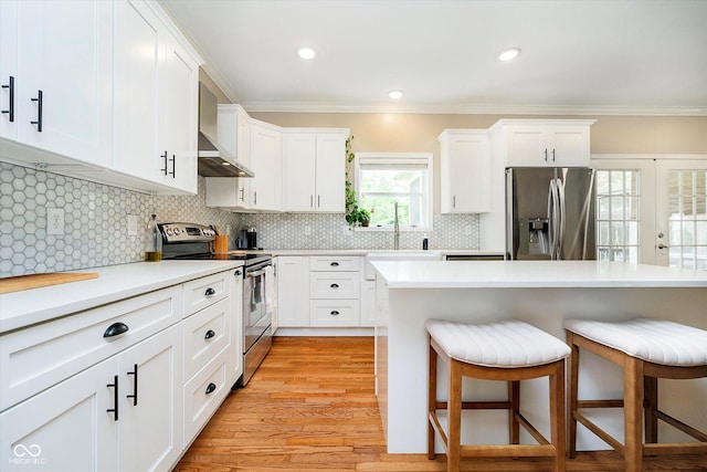 11141 Saybrook Ct, Fishers, IN 46037 - kitchen featuring appliances with stainless steel finishes, wall chimney exhaust hood, a breakfast bar, crown molding, and light countertops