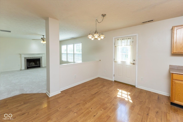 6516 Amherst Way, Zionsville, IN 46077 - unfurnished dining area featuring ceiling fan, plenty of natural light, a fireplace, light wood-style floors, and a textured ceiling
