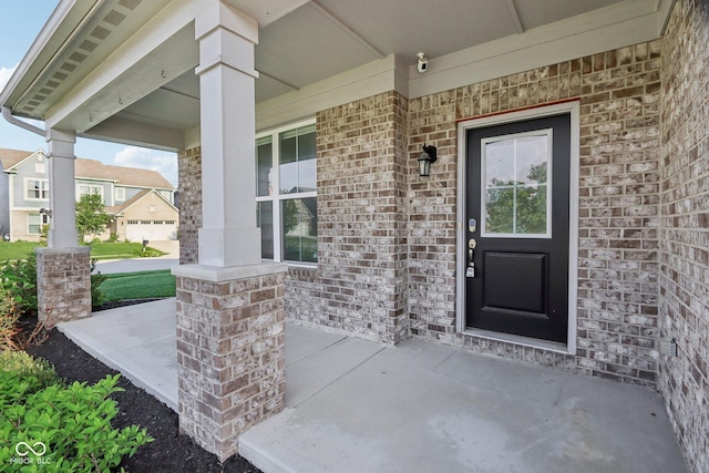 doorway to property featuring covered porch and brick siding