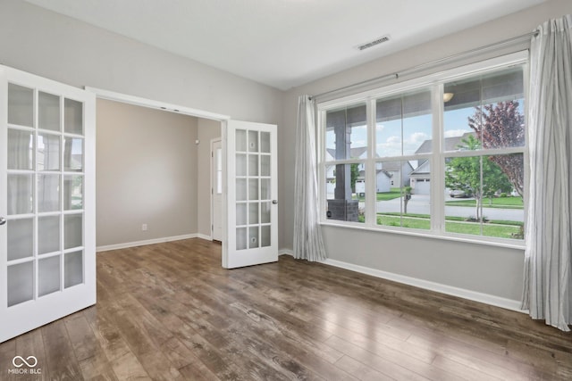 spare room featuring french doors, hardwood / wood-style flooring, and baseboards