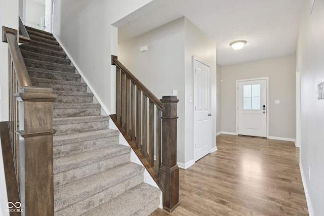 entryway featuring wood finished floors, stairway, and baseboards