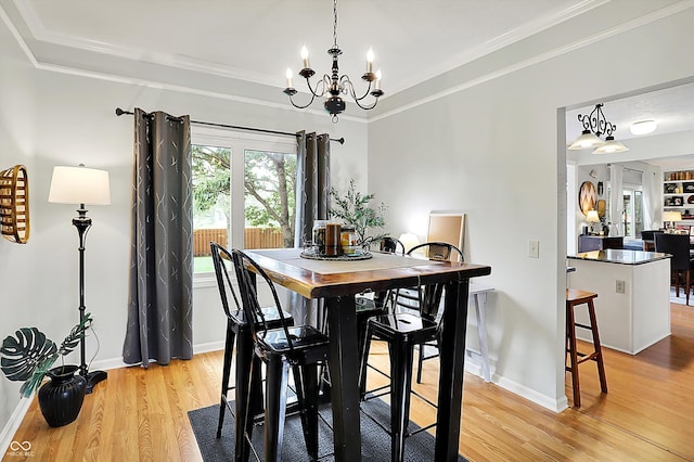dining space featuring crown molding, baseboards, a chandelier, and light wood-style flooring