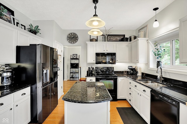 kitchen featuring a center island, a sink, black appliances, light wood-style floors, and white cabinetry
