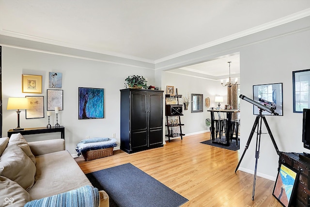 living area featuring baseboards, ornamental molding, light wood finished floors, and a chandelier