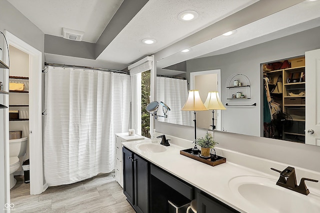 full bathroom featuring double vanity, toilet, recessed lighting, and a sink