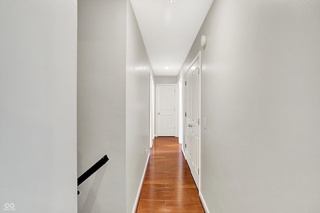 hall featuring baseboards, wood finished floors, and an upstairs landing