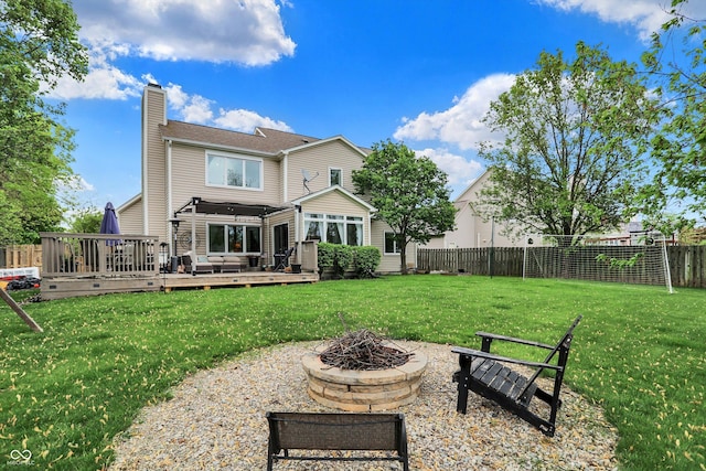rear view of property featuring a fenced backyard, a fire pit, a yard, and a chimney