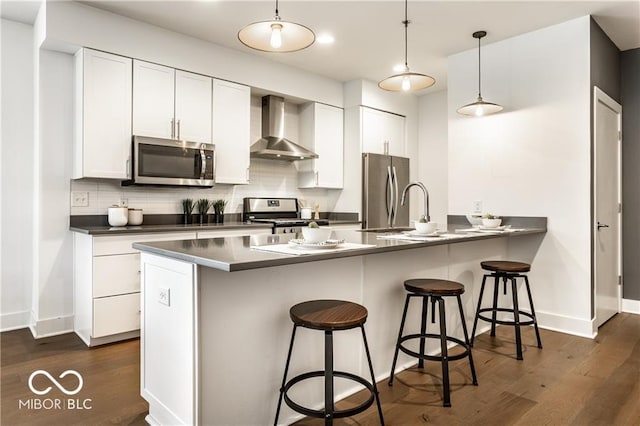 622 E 10th St Unit 212, Indianapolis, IN 46202 - kitchen featuring a breakfast bar, wall chimney exhaust hood, stainless steel appliances, tasteful backsplash, and dark wood-style floors