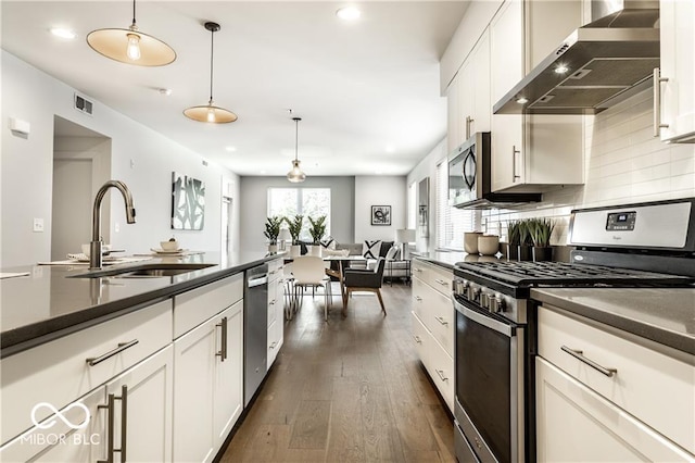622 E 10th St Unit 212, Indianapolis, IN 46202 - kitchen featuring visible vents, dark countertops, wall chimney range hood, a sink, and appliances with stainless steel finishes