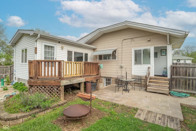 back of property with fence, a wooden deck, and a patio area