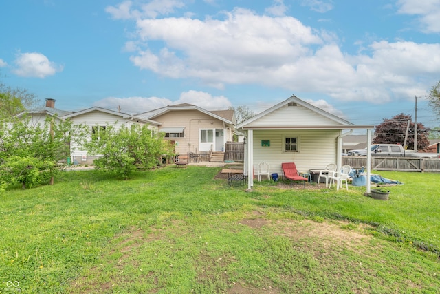 rear view of house featuring fence and a lawn