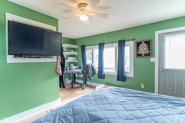 bedroom featuring baseboards, a textured ceiling, ceiling fan, and wood finished floors