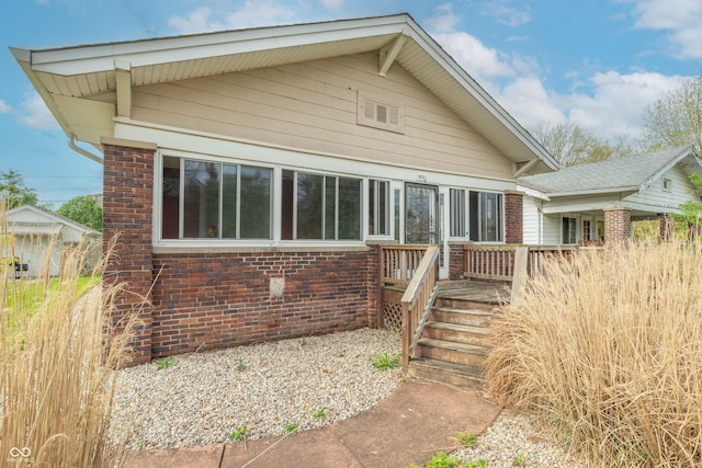 rear view of house featuring brick siding and a deck