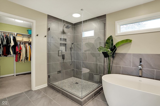full bathroom with a spacious closet, a shower stall, a soaking tub, and tile patterned flooring