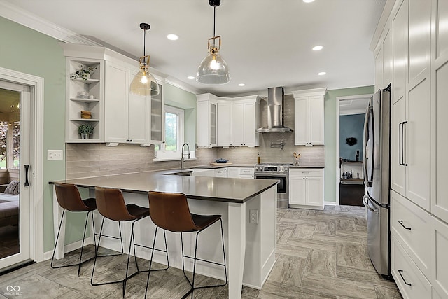kitchen featuring a peninsula, appliances with stainless steel finishes, white cabinetry, and wall chimney exhaust hood
