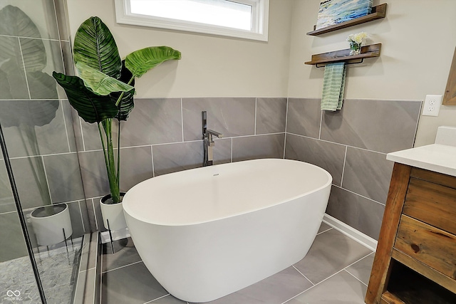 full bathroom featuring tile walls, a soaking tub, tile patterned flooring, and vanity