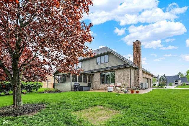 rear view of property with an attached garage, brick siding, a sunroom, a chimney, and a yard