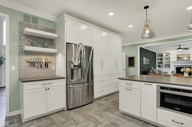 kitchen featuring ceiling fan, appliances with stainless steel finishes, open floor plan, visible vents, and ornamental molding