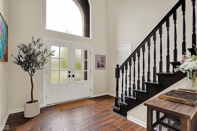 foyer entrance featuring baseboards, stairs, dark wood-type flooring, and a healthy amount of sunlight