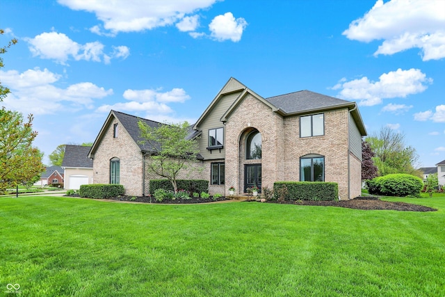 view of front of home with a shingled roof, a front yard, and brick siding
