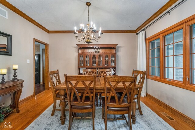 4401 W Hunters Ridge Ln W, Greenwood, IN 46143 - dining space featuring crown molding, visible vents, baseboards, a chandelier, and light wood finished floors