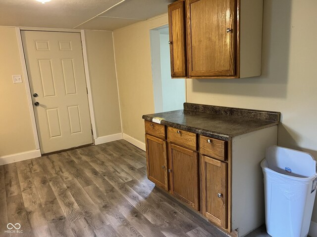 kitchen with dark countertops, baseboards, brown cabinetry, and dark wood-type flooring