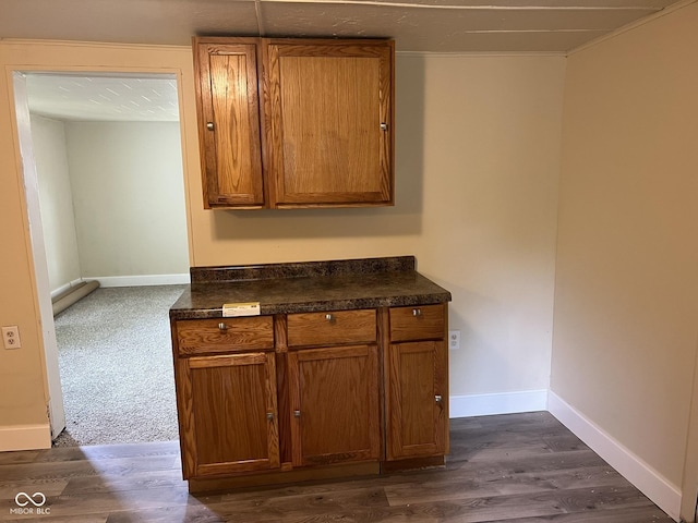interior space with baseboards, dark wood finished floors, brown cabinets, and dark countertops