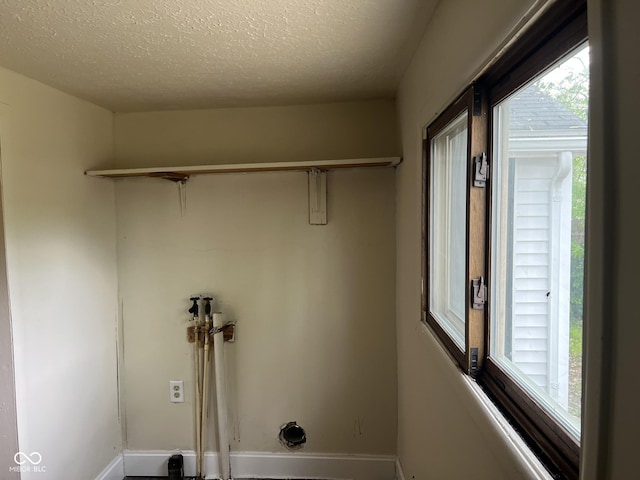laundry room featuring baseboards, laundry area, and a textured ceiling