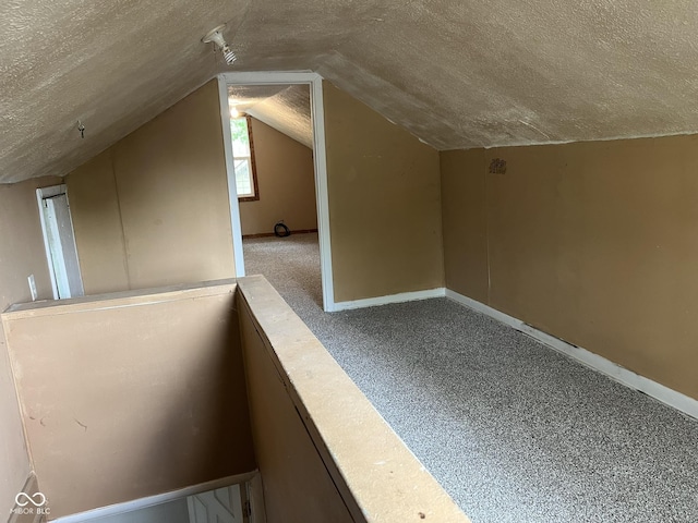 bonus room with a textured ceiling, vaulted ceiling, baseboards, and carpet