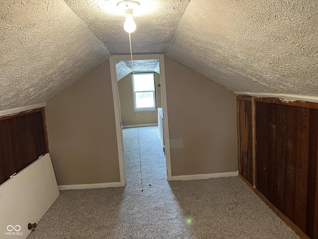 bonus room with baseboards, a textured ceiling, carpet, and lofted ceiling