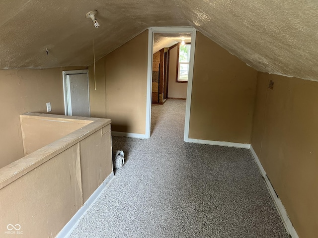 additional living space featuring baseboards, carpet flooring, a textured ceiling, and lofted ceiling